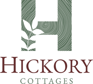 Apartments in Lebanon, IN Logo for Hickory Cottages featuring a stylized green letter 'H' with a tree ring pattern and white leaf graphic, and the text "Hickory Cottages" in bold maroon font below.