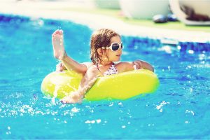 Apartments in Lebanon Young girl enjoying the pool with float ring and sunglasses on a sunny day.