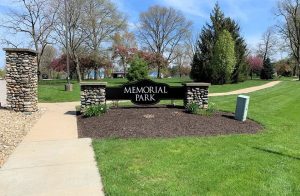 Apartments in Lebanon, IN Entrance sign of memorial park with flowerbeds, green lawns, and trees under a clear sky.