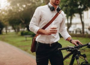 Apartments in Lebanon Man with headphones around neck holding a coffee cup while standing next to a bicycle outdoors.