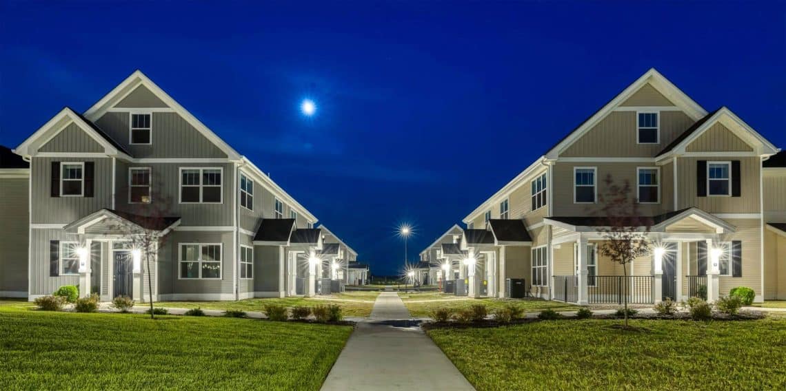 Indiana, Boone County, Lebanon Apartments for rent A well-lit residential area at night showcases two rows of modern townhouses with peaked roofs, separated by a walkway and grassy lawns. Under a clear sky with a visible moon, these new apartments in Lebanon IN offer contemporary living in serene surroundings. See all available apartments for rent at Hickory Cottages in Indiana Boone County Lebanon, Hickory Cottages has rental units ranging from 664-1420 sq ft