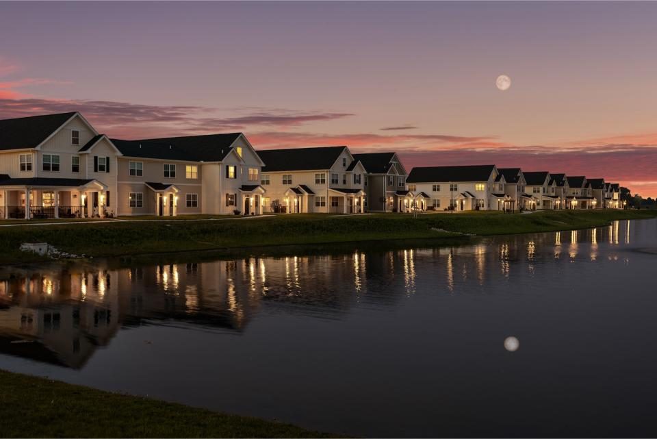 Indiana, Boone County, Lebanon Apartments for rent Row of modern houses with lights on, reflected in a calm pond at sunset, with a visible moon and colorful sky in the background. See all available apartments for rent at Hickory Cottages in Indiana Boone County Lebanon, Hickory Cottages has rental units ranging from 664-1420 sq ft