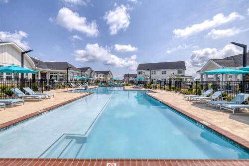 Apartments in Lebanon, IN An outdoor swimming pool with lounge chairs, umbrellas, and surrounding buildings on a sunny day.