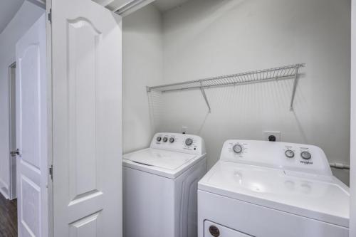 Apartments in Lebanon, IN A laundry room with a white washing machine and dryer, open folding doors, and a wire shelf mounted above the appliances.