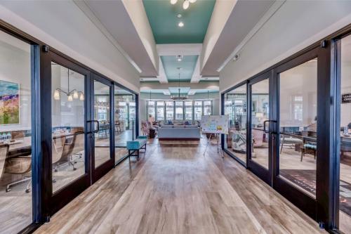 Apartments in Lebanon, IN A modern office space with glass-walled conference rooms on both sides, a seating area at the far end, and contemporary decor. The space features wooden flooring and teal accents.