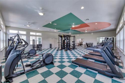 Apartments in Lebanon, IN A modern gym with various exercise equipment, including treadmills, elliptical machines, stationary bikes, and weight sets, in a spacious room with checkered flooring and large windows.