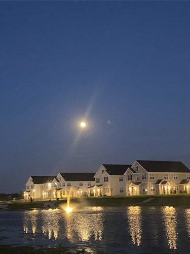 Indiana, Boone County, Lebanon Apartments for rent Row of townhouses at dusk with lights on, a fountain in a pond, and a bright full moon in the evening sky. See all available apartments for rent at Hickory Cottages in Indiana Boone County Lebanon, Hickory Cottages has rental units ranging from 664-1420 sq ft