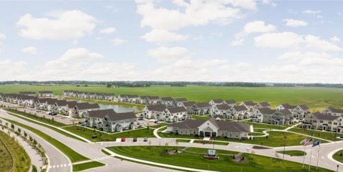 Indiana, Boone County, Lebanon Apartments for rent Aerial view of a suburban neighborhood with rows of houses, green lawns, wide streets, and an open field in the background under a partly cloudy sky. See all available apartments for rent at Hickory Cottages in Indiana Boone County Lebanon, Hickory Cottages has rental units ranging from 664-1420 sq ft