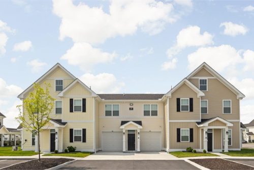 Indiana, Boone County, Lebanon Apartments for rent Two adjacent two-story townhouses with beige and yellow siding, each with a garage, small porches, and a single young tree in front, under a partly cloudy sky. See all available apartments for rent at Hickory Cottages in Indiana Boone County Lebanon, Hickory Cottages has rental units ranging from 664-1420 sq ft