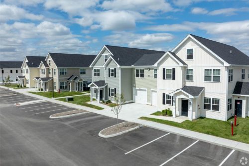 Indiana, Boone County, Lebanon Apartments for rent Row of modern, two-story townhouses with garages and front lawns, adjacent to an empty parking lot under a partly cloudy sky. See all available apartments for rent at Hickory Cottages in Indiana Boone County Lebanon, Hickory Cottages has rental units ranging from 664-1420 sq ft
