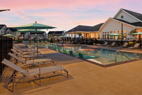 Indiana, Boone County, Lebanon Apartments for rent Outdoor swimming pool area at sunset with lounge chairs, umbrellas, and poolside buildings in the background. The pool has in-water loungers and a surrounding patio. See all available apartments for rent at Hickory Cottages in Indiana Boone County Lebanon, Hickory Cottages has rental units ranging from 664-1420 sq ft