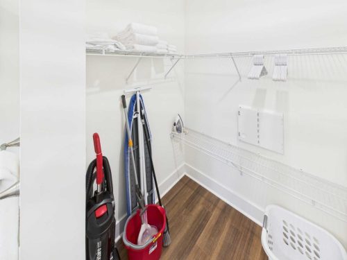 Indiana, Boone County, Lebanon Apartments for rent A closet with wire shelves holding towels and hangers, a vacuum cleaner, mop and bucket, ironing board, iron, and a laundry basket on a wood floor. See all available apartments for rent at Hickory Cottages in Indiana Boone County Lebanon, Hickory Cottages has rental units ranging from 664-1420 sq ft