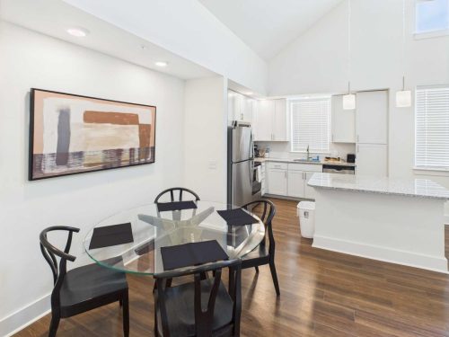 Indiana, Boone County, Lebanon Apartments for rent Modern kitchen and dining area with a round glass table, four black chairs, abstract wall art, and white cabinetry with stainless steel appliances. See all available apartments for rent at Hickory Cottages in Indiana Boone County Lebanon, Hickory Cottages has rental units ranging from 664-1420 sq ft
