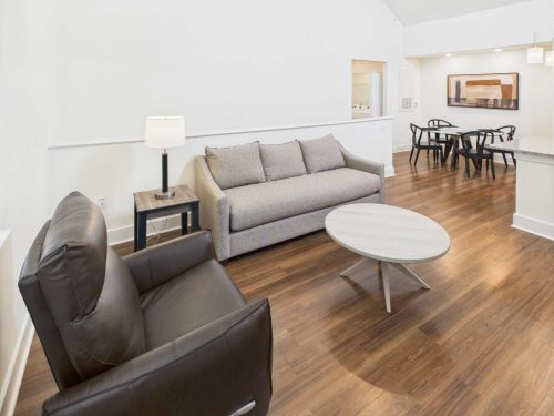 Indiana, Boone County, Lebanon Apartments for rent Modern living space with a gray sofa, black armchair, round coffee table, wood flooring, and a dining area with black chairs in the background. See all available apartments for rent at Hickory Cottages in Indiana Boone County Lebanon, Hickory Cottages has rental units ranging from 664-1420 sq ft