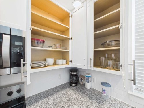 Indiana, Boone County, Lebanon Apartments for rent Open white kitchen cabinets displaying neatly organized dishes, glasses, and bowls above a granite countertop with a coffee maker and small appliances. See all available apartments for rent at Hickory Cottages in Indiana Boone County Lebanon, Hickory Cottages has rental units ranging from 664-1420 sq ft