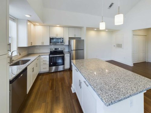 Indiana, Boone County, Lebanon Apartments for rent Modern kitchen with white cabinets, stainless steel appliances, granite countertops, center island, and wood flooring under pendant lights. See all available apartments for rent at Hickory Cottages in Indiana Boone County Lebanon, Hickory Cottages has rental units ranging from 664-1420 sq ft
