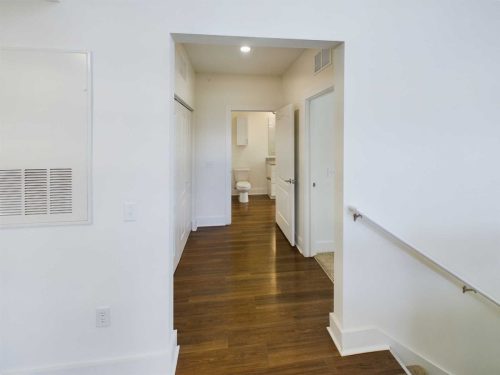 Indiana, Boone County, Lebanon Apartments for rent View of a hallway with wood floors leading to a bathroom with an open door; white walls and a handrail are visible on the right. See all available apartments for rent at Hickory Cottages in Indiana Boone County Lebanon, Hickory Cottages has rental units ranging from 664-1420 sq ft