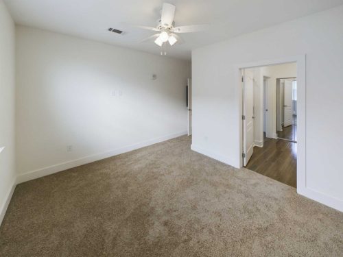 Indiana, Boone County, Lebanon Apartments for rent Empty room with beige carpet, white walls, ceiling fan with lights, and open double doors leading to a hallway with wood flooring. See all available apartments for rent at Hickory Cottages in Indiana Boone County Lebanon, Hickory Cottages has rental units ranging from 664-1420 sq ft
