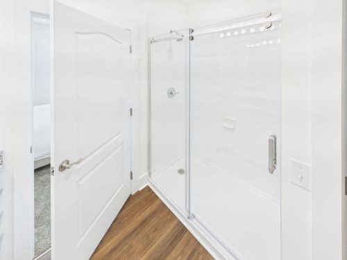 Indiana, Boone County, Lebanon Apartments for rent A modern bathroom features a glass-enclosed shower with white tile walls, a chrome showerhead, and a sliding door. The floor is wood-style, and the door to the room is open. See all available apartments for rent at Hickory Cottages in Indiana Boone County Lebanon, Hickory Cottages has rental units ranging from 664-1420 sq ft