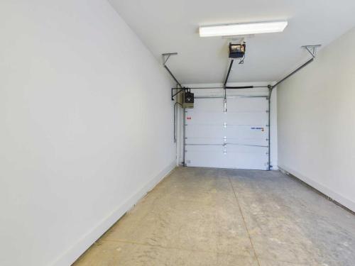 Apartments in Lebanon, IN An empty, clean garage interior with white walls, a closed garage door, and fluorescent lighting on the ceiling.
