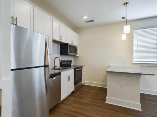 Apartments in Lebanon, IN Modern kitchen with white cabinets, stainless steel appliances, granite countertops, a breakfast bar, and hardwood floors.