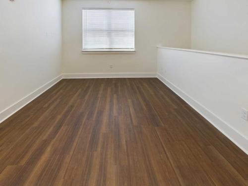 Apartments in Lebanon, IN An empty room with white walls, a window with closed blinds, and wooden flooring.