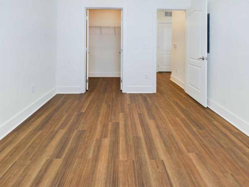 Apartments in Lebanon, IN Empty room with light brown hardwood flooring, white walls, and two open doors. One door leads to a small closet and the other to another room.