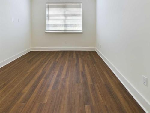 Apartments in Lebanon, IN An empty room with white walls, a window with blinds, and a wooden floor.