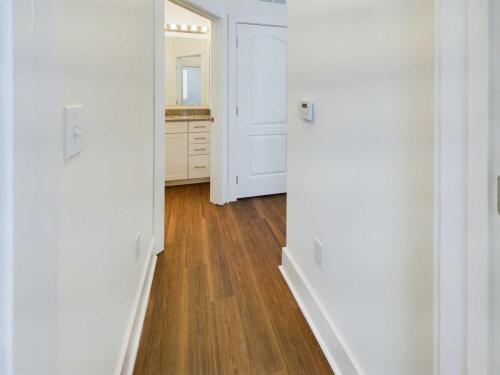 Apartments in Lebanon, IN A hallway with wooden floors leads to a well-lit bathroom with white cabinets and a granite countertop.