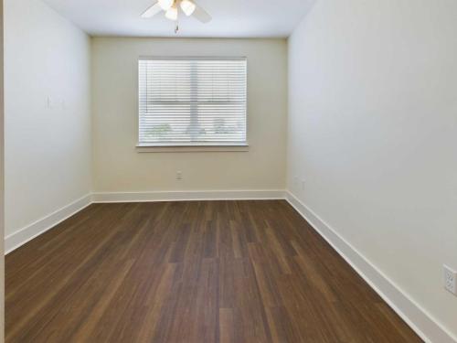 Apartments in Lebanon, IN Empty room with white walls, a ceiling fan, and a window with blinds. The room has brown wooden flooring and white baseboards.