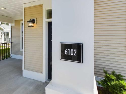 Apartments in Lebanon, IN A house entrance with the address number "6102" displayed on a plaque beside the door under a wall-mounted light.