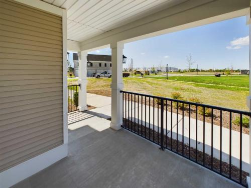 Apartments in Lebanon, IN Residential porch with white columns and black railing, overlooking a suburban neighborhood with green lawns, houses, and cars in the background.