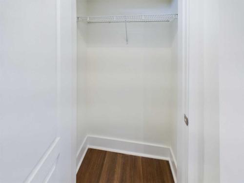 Apartments in Lebanon, IN An empty closet with white walls, a wooden floor, and a metal wire shelf near the top.