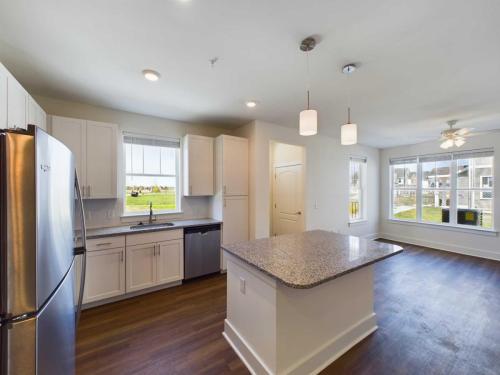 Apartments in Lebanon, IN Modern kitchen with stainless steel appliances, white cabinets, granite kitchen island, and large windows allowing natural light. The open floor plan connects the kitchen to a bright living area.