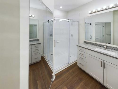 Apartments in Lebanon, IN Modern bathroom with glass-enclosed shower, vanity with sink and large mirror, and wood flooring.