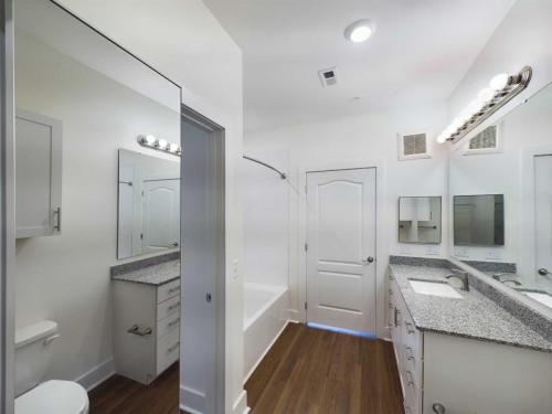 Apartments in Lebanon, IN A modern bathroom with a bathtub-shower combo, dual sinks with granite countertops, large mirror, recessed lighting, and wood flooring.