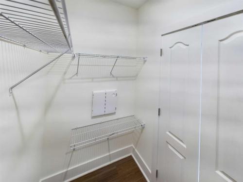 Apartments in Lebanon, IN Empty walk-in closet with white walls, wooden floor, wire shelving, and a closed white door. Perfect for organizing your belongings in one of the cozy apartments for rent in Lebanon, Indiana.