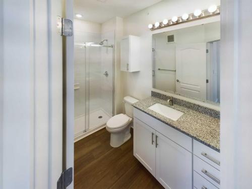 Apartments in Lebanon, IN A modern bathroom in one of the beautiful apartments for rent in Lebanon, Indiana features a glass shower enclosure, a toilet, and a granite countertop sink with a large mirror above. The vanity has white cabinets and drawers. The floor is wooden.