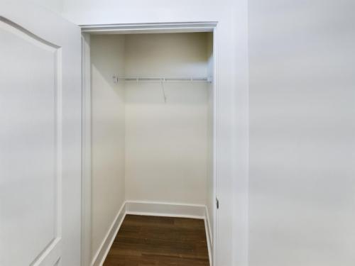 Apartments in Lebanon, IN Empty white closet with a wooden floor, open door, and a single wire shelf attached to the back wall.