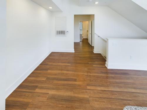 Apartments in Lebanon, IN An empty room with wooden flooring and white walls. A hallway leads to other rooms.