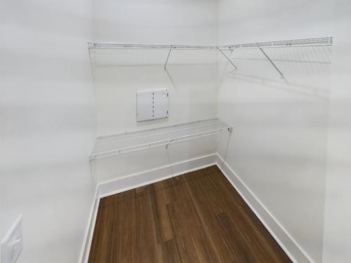 Apartments in Lebanon, IN Empty walk-in closet with white walls, wooden floor, and metal wire shelving on two sides.