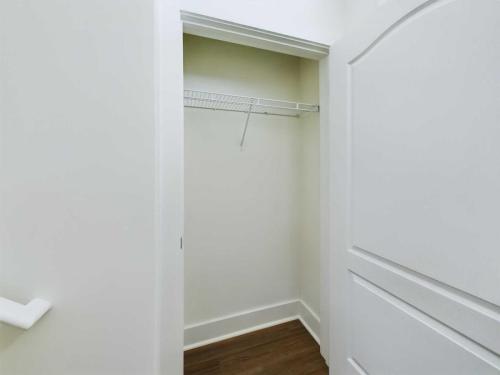 Apartments in Lebanon, IN Open white closet with a single wire shelf, empty interior, and wooden flooring visible at the bottom.