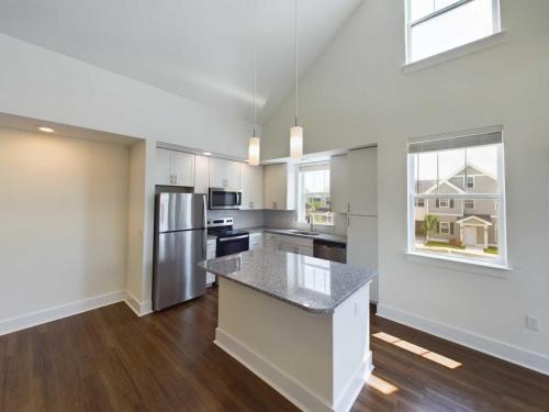 Apartments in Lebanon, IN A modern kitchen featuring stainless steel appliances, a central island with granite countertops, pendant lights, and large windows providing ample natural light.