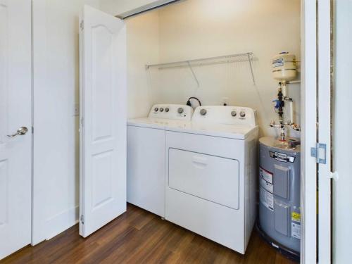 Apartments in Lebanon, IN A small laundry closet with a washing machine, dryer, and water heater, with folding white doors and a shelf above the appliances.