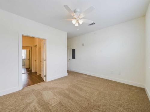 Apartments in Lebanon, IN A vacant, carpeted room with white walls, a ceiling fan with lights, and an open doorway leading to another part of the house.