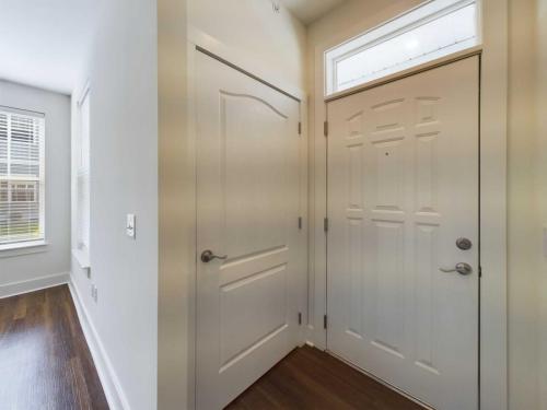 Apartments in Lebanon, IN A white entryway with a closed front door, adjacent closet door, and window with blinds, featuring dark hardwood flooring.