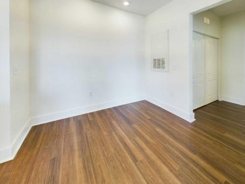 Apartments in Lebanon, IN A room with white walls, a wooden floor, a closet with closed white double doors, and a vent on the wall. The space is empty and well-lit.