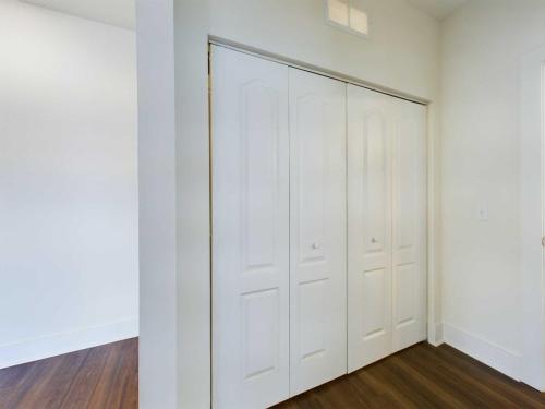 Apartments in Lebanon, IN A white double-door closet with recessed panels, set against a white wall and dark wood flooring.