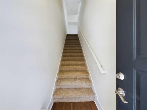 Apartments in Lebanon, IN Open door revealing a carpeted staircase ascending between white walls. The handrail runs along the right side. The view extends to the top of the stairs where a ceiling light is visible.