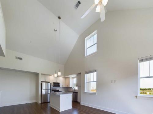 Apartments in Lebanon, IN Bright and spacious kitchen and living area with high, vaulted ceilings, white walls, wood flooring, stainless steel appliances, and large windows letting in natural light.